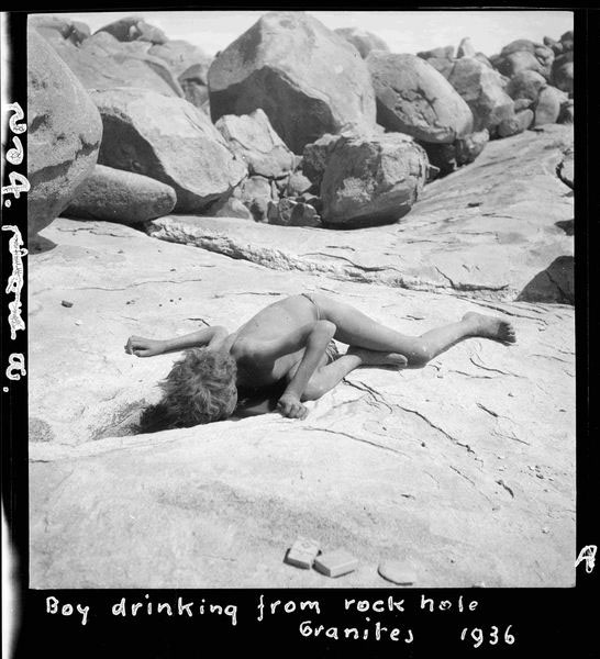 Boy drinking from a rock-hole at the granites, 1936. Photo by CP Mountford.
