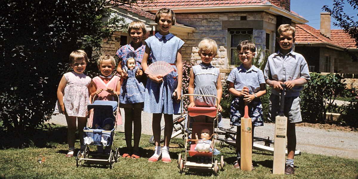 Seven children posing for a photo in front of a house, holding their Christmas toys