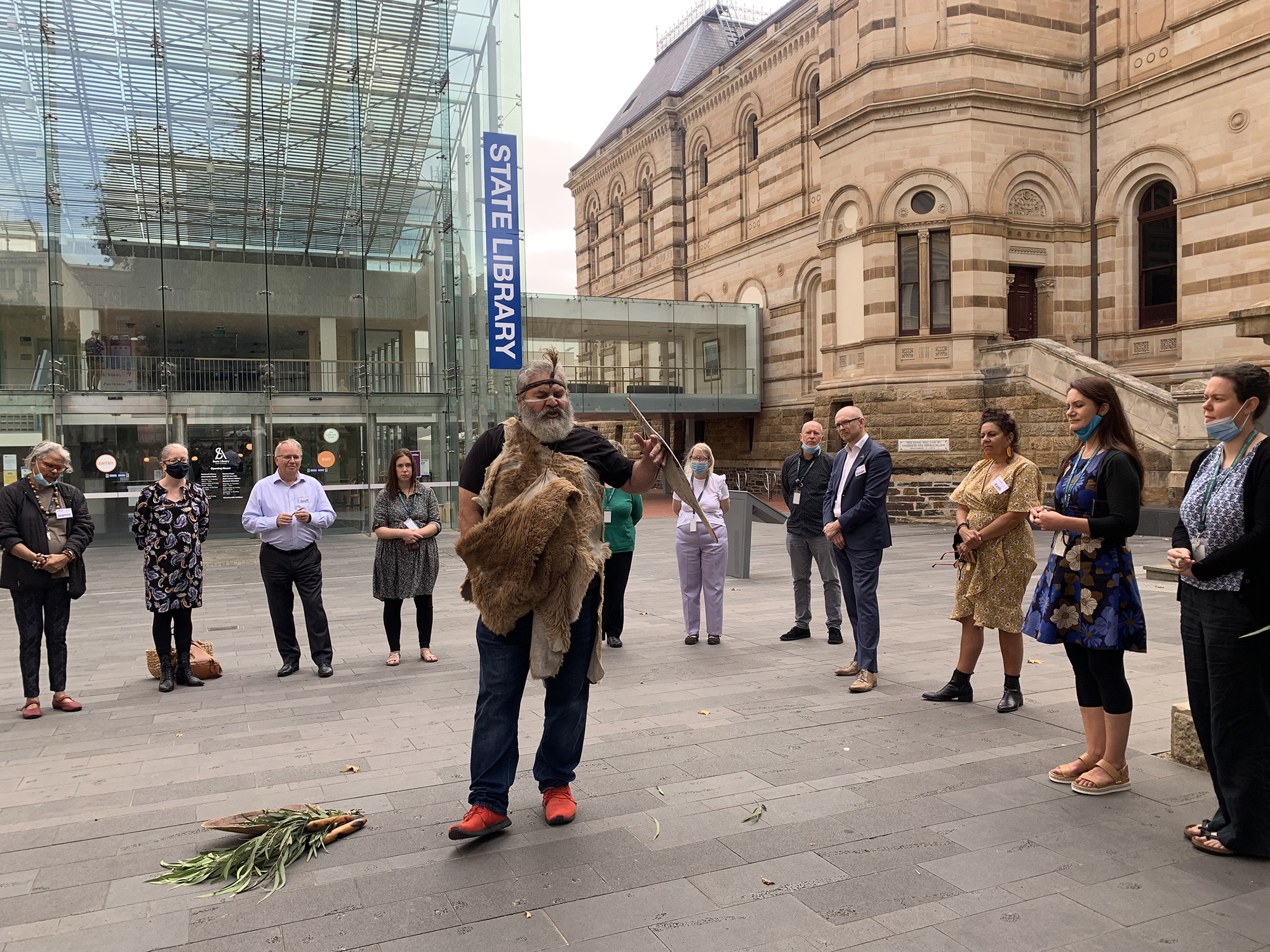 People standing in a circle for an Aboriginal smoking ceremony.