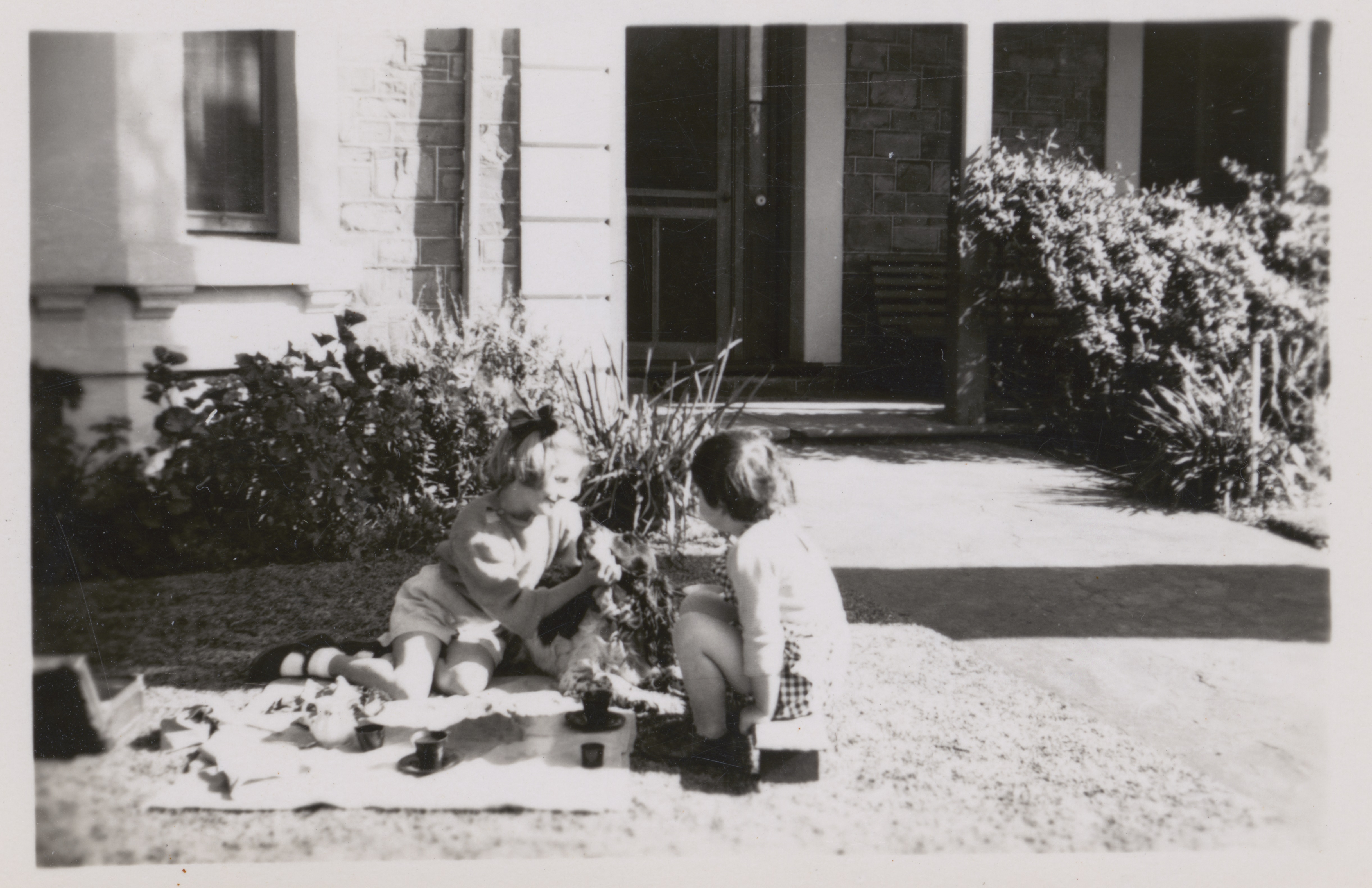 Children Rosemary and Gabrielle take tea on the lawn with their dog, in Largs Bay, 28th August 1948.