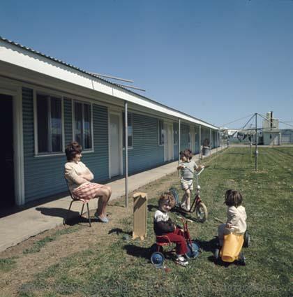 A lady with three children on their bikes outside at the Pennington Migrant Hostel