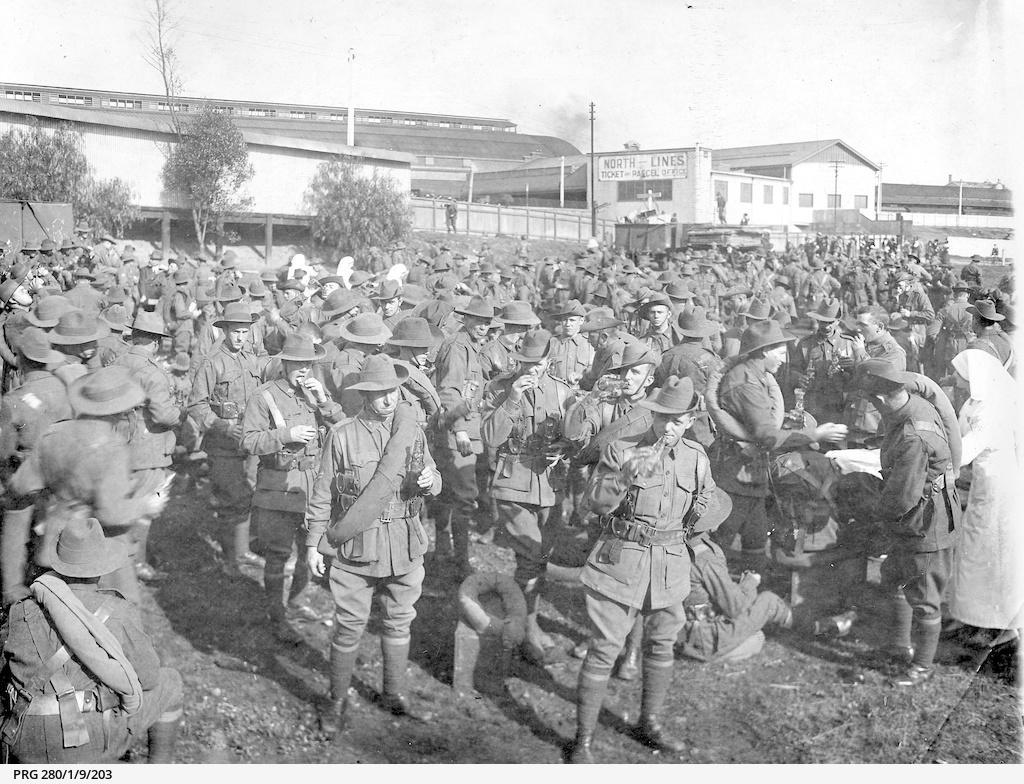 Departing soldiers at Adelaide railway station receiving food and drink from women Cheer Up Hut volunteers.