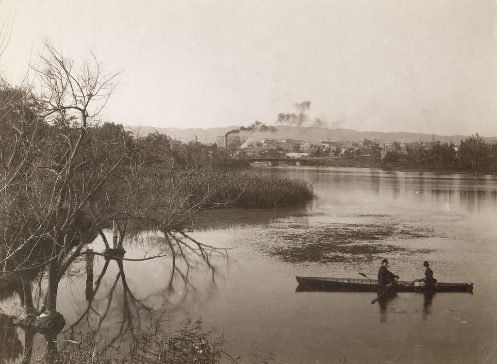 Two men in rowboat, view of Adelaide in distance, c 1880