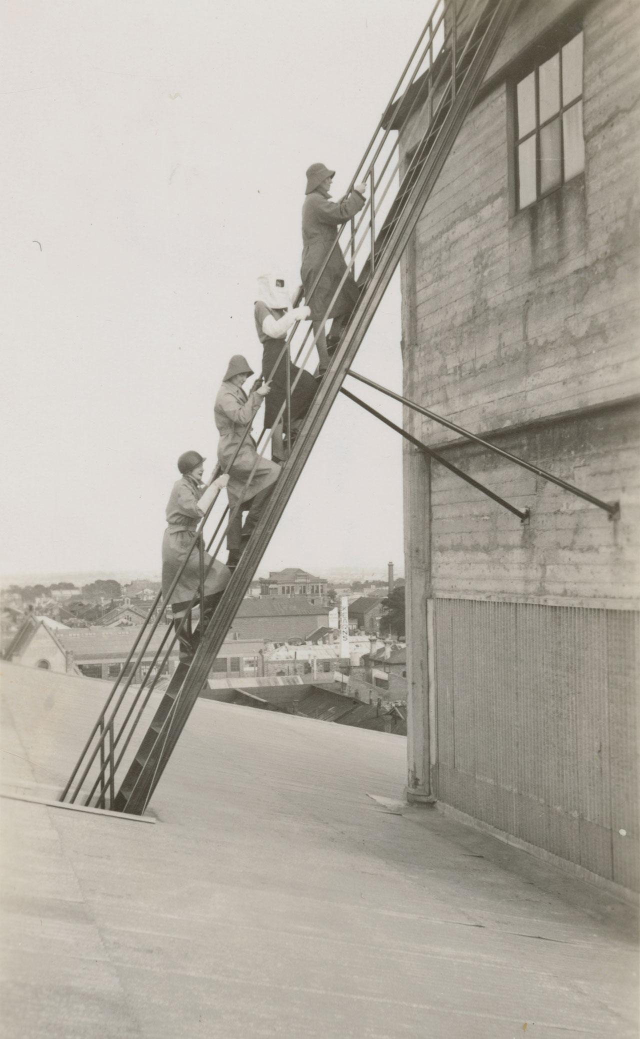 Women climbing the steel ladder from the rear of the watching post.