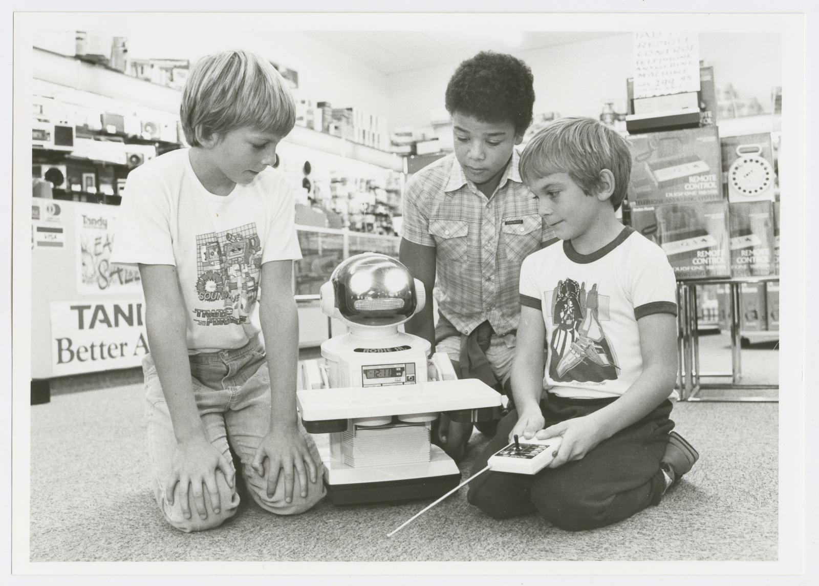 Three boys playing with a remote controlled robot