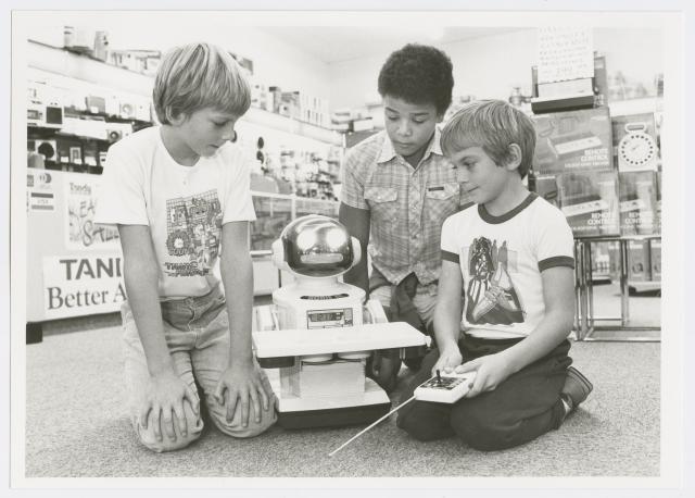 Three boys playing with a remote controlled robot