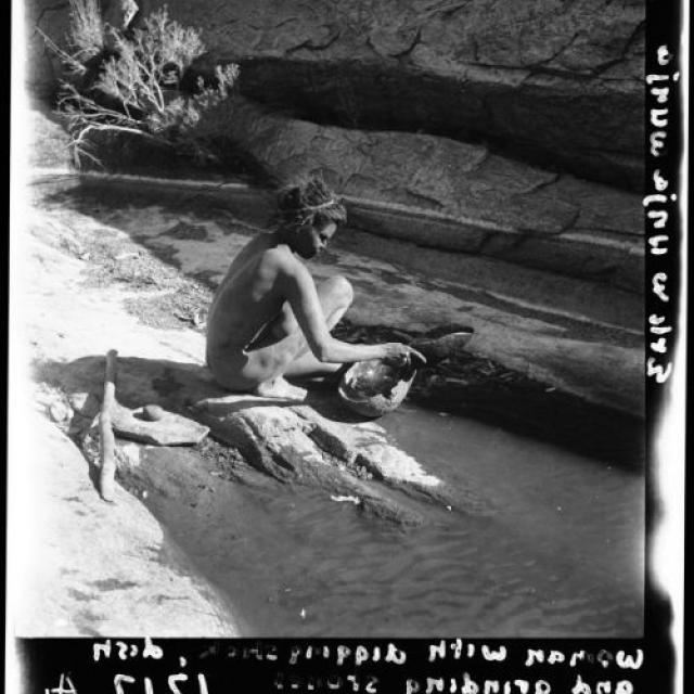 Aboriginal woman collecting water in a dish at Aliwanyuwanyu rockhole, Musgrave Ranges, 1940. SLSA: PRG 1218/34/1217A