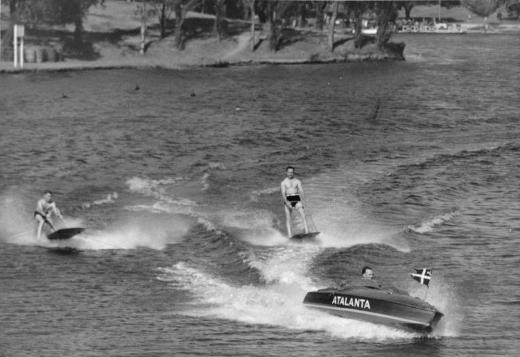 Two men on large aquaplane boards towed by small speedboat, 1938.