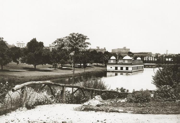 Floating Palais moored at lakeside; landscaped paths and rustic fence in foreground.