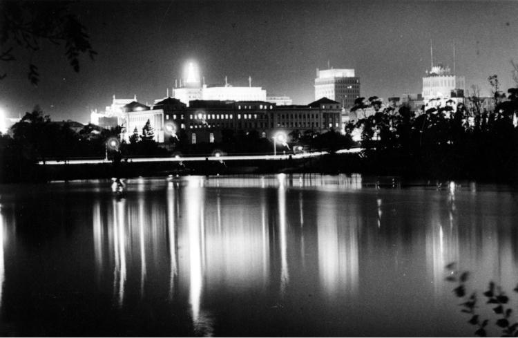 Black and white nightview over lake, buildings reflected in water, c 1940 