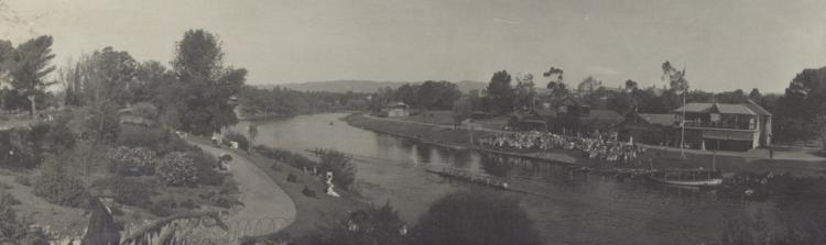 Onlookers on banks watch boats on water, c 1912
