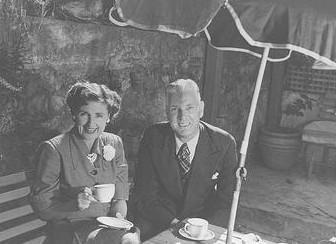Max and Thelma sitting at outdoor table under umbrella 